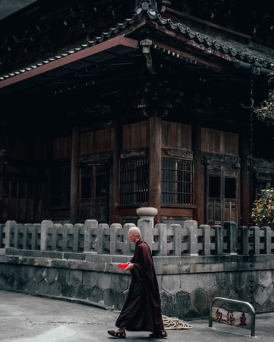 女人黑色和红色的裙子站在白天褐色的木房子
